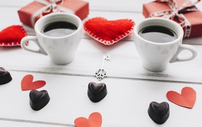 Two cups of coffee on the table with gifts, sweets and hearts