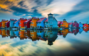 Beautiful colorful houses are reflected in the water under a beautiful sky.