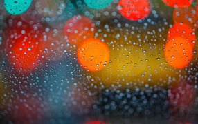 Drops of rain on the glass with multicolored highlights