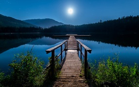 Wooden bridge on the lake in full moon