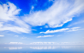 Красивые белые облака над водой около заснеженных гор