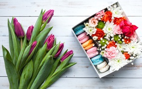 Букет сиреневых тюльпанов на столе с коробкой с макарунами