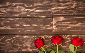 Три красные розы на деревянном фоне