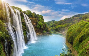 Красивый водопад стекает с утеса под голубым небом