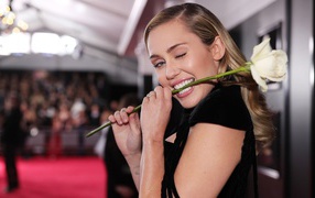 Singer Miley Cyrus with a rose in her teeth