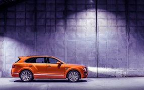 Оранжевый автомобиль Bentley Bentayga вид сбоку