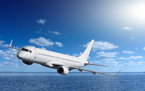 Большой белый пассажирский самолет летит над морем