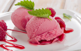 Two balls of raspberry ice cream on a plate with berries