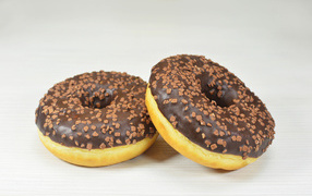 Two sweet donuts with chocolate on a gray background