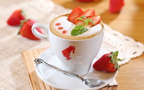 A cup of cappuccino with strawberries on the table