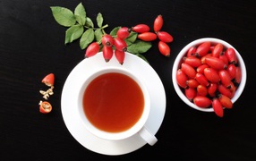 A cup of tea on the table with wild rose berries