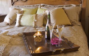 Champagne with glasses and a candle on the bed