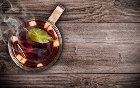 Glass cup of hot tea on a wooden table