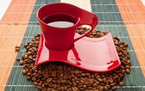 Красная чашка стоит на кофейных зернах 
