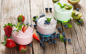 Three glasses of smoothies with berries on a wooden table