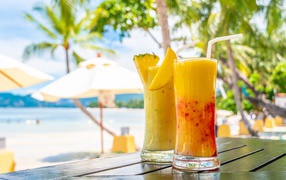 Two citrus cocktails on a table on a tropical beach