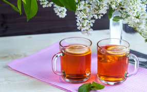 Две чашки чая с лимоном на столе с цветами 