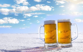 Два бокала пива стоят на белом снегу под голубым небом