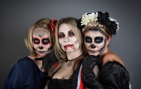Three girls with masks and Halloween costumes