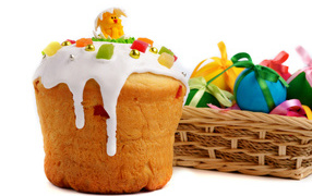 Красивый пасхальный кулич на белом фоне с корзиной крашеных яиц к празднику Пасха