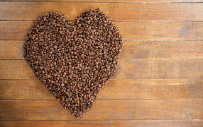 Большое сердце из кофейных зерен на деревянном столе