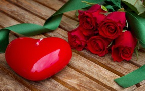 Big heart on a wooden table with a bouquet of red roses