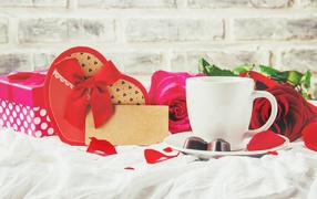 Box with a gift on the table with a cup of coffee and red roses
