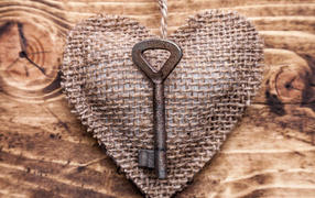 Сердечко из мешковины с ключом на деревянном фоне