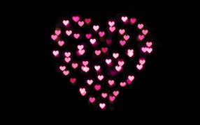 Heart made of small pink hearts on a black background