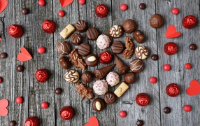 Сердце из шоколадных конфет ассорти на деревянном столе для любимой 