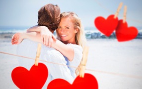 Loving couple on the seashore with red hearts