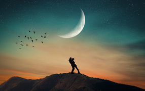 Loving couple stands on a mountain against the background of the moon