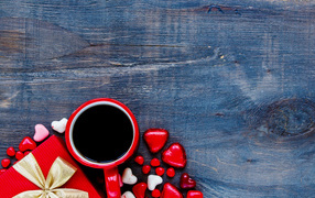 Red cup of coffee, hearts and gift on wooden background