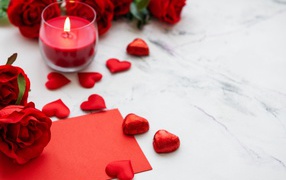 Red hearts, a lit candle and roses for a loved one