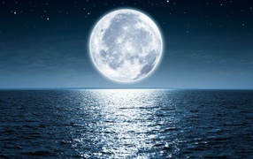 A huge white moon in the starry sky above the sea