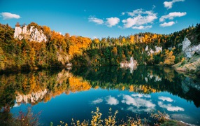 Blue sky and forest reflected in the water of a clean mountain lake