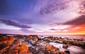 Каменный берег в море на закате солнца