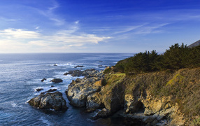 Каменные скалы береговой линии в океане под голубым небом