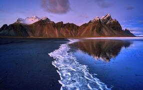 Water on the black sand on the background of mountains