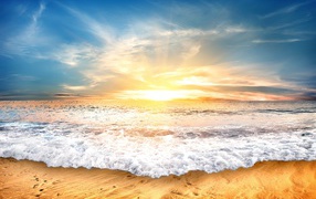 Белые волны на желтом песке на закате солнца 