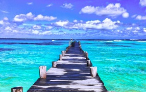 Wooden wet pier in the blue ocean under a beautiful sky