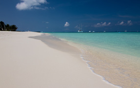 Calm waves on white hot sand under a blue sky
