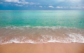 Волны голубого океана на желтом песке под голубым небом