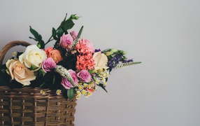 A bouquet of flowers in a basket on a gray background