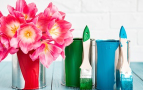 Букет розовых тюльпанов на столе с банками краски и кисточками