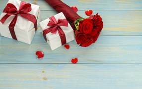 Букет красных роз с подарками на столе