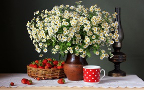A large bouquet of daisies on a table with strawberries