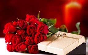 A large bouquet of red roses with a gift