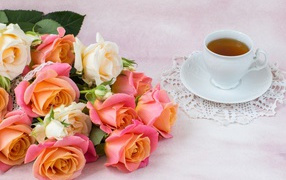 Красивый букет нежных роз на столе с чашкой чая