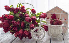 Красивый букет красных тюльпанов на столе с клубникой 